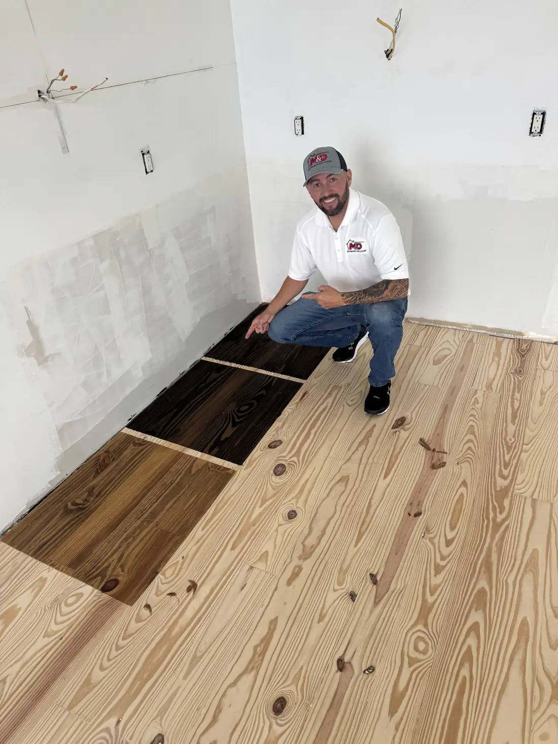 Marcos, founder of M&D, beside stain color samples on a sanded floor
