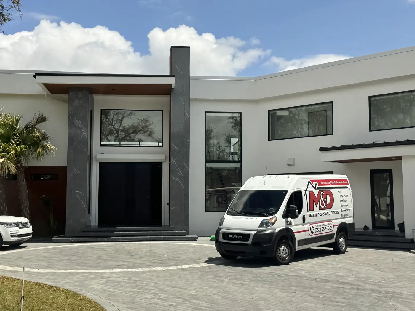 An M&D branded van parked outside a modern home on a job