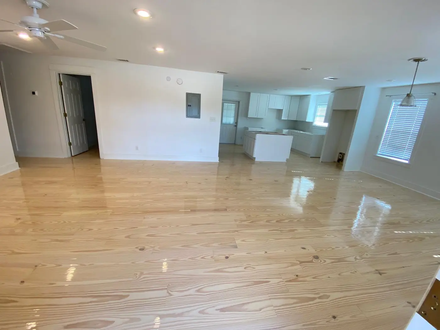 Open-plan living area with a high-gloss wood floor and new kitchen
