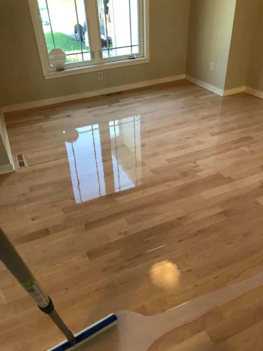 Finish being applied to a sanded hardwood floor