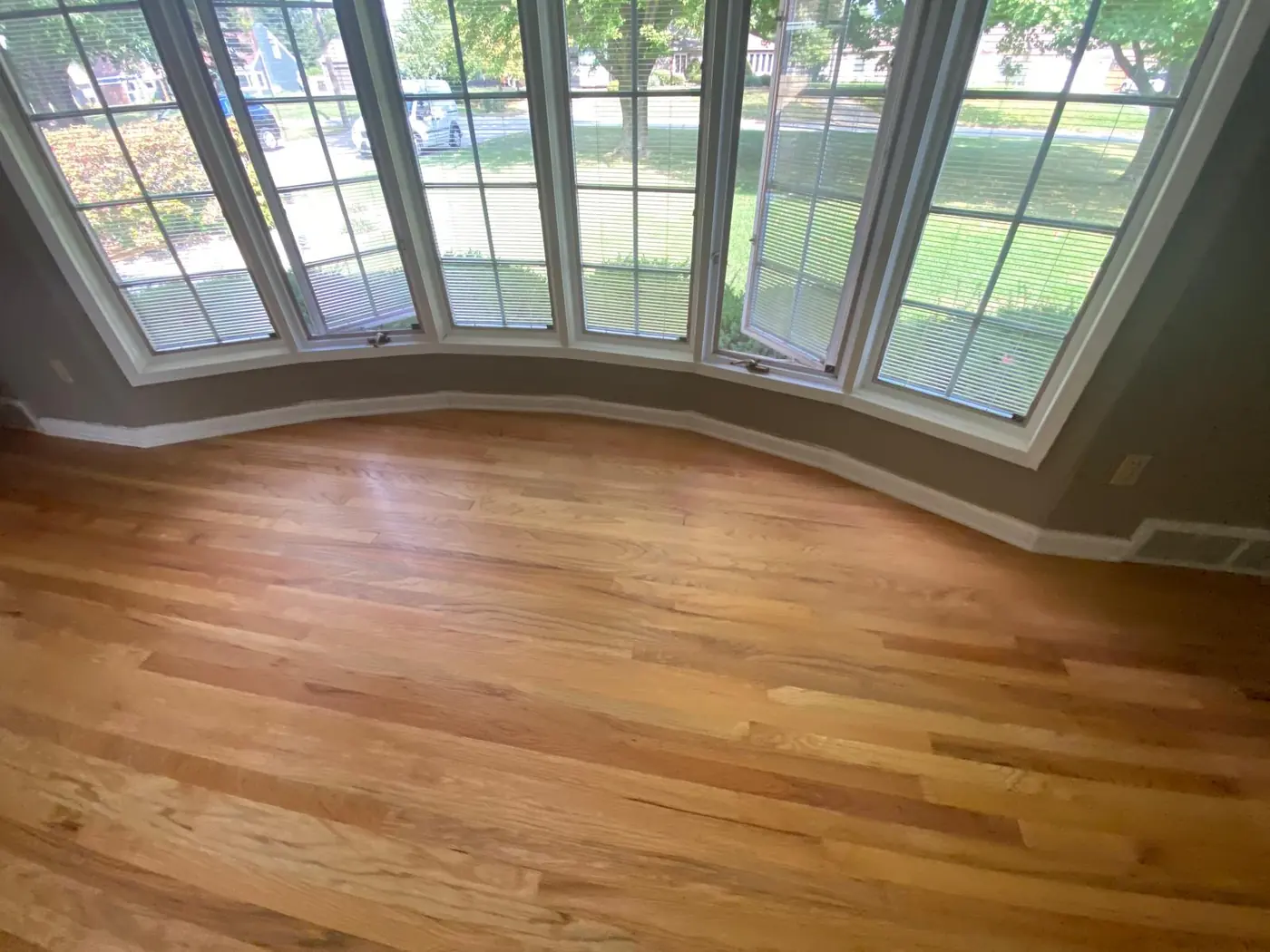 Finished hardwood floor in a room with a curved bay window