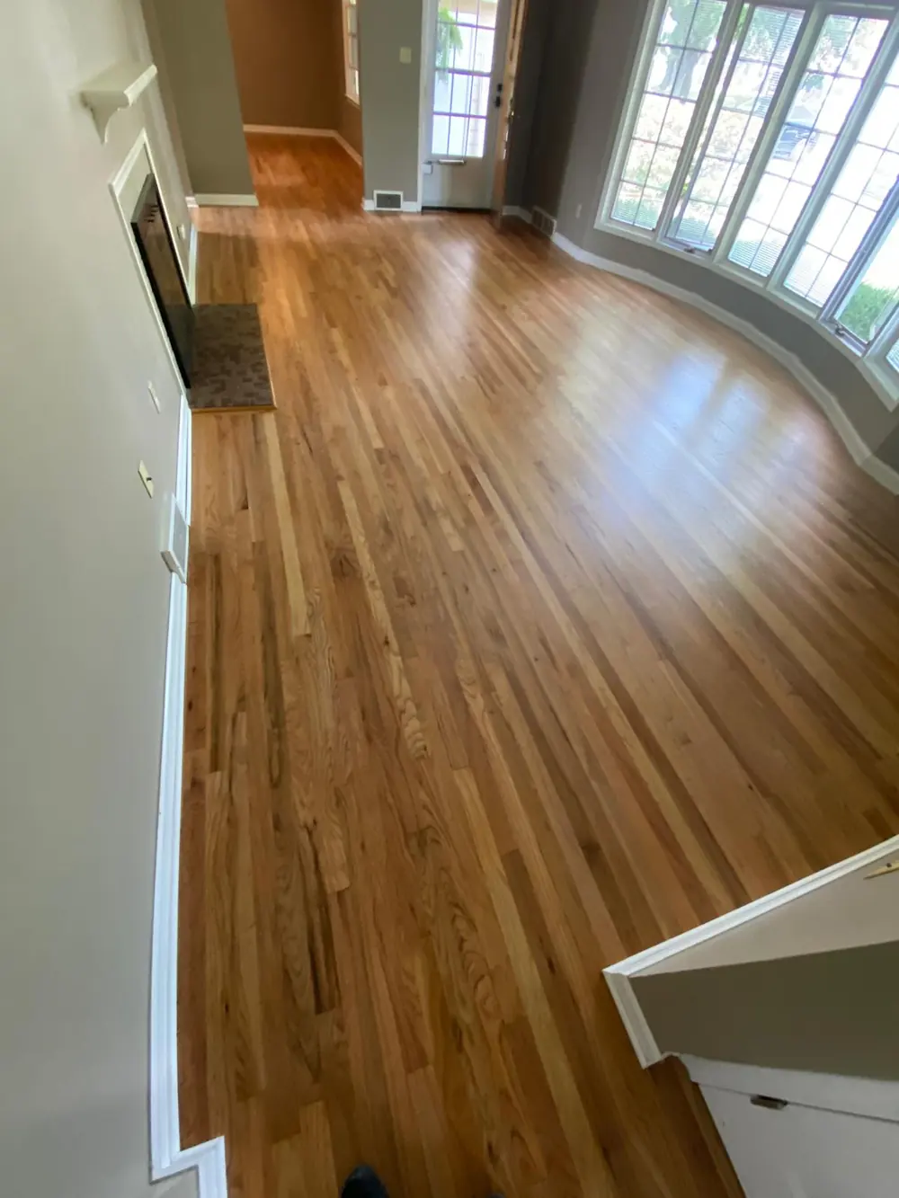 Finished hardwood floor through a living room with a fireplace
